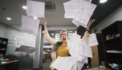 Stressed woman throws papers in the office in an image of relief