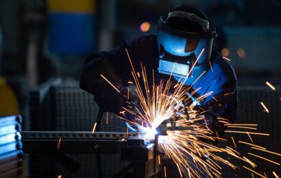 Workers wearing industrial uniforms and Welded Iron Mask at Steel welding plants, industrial safety first concept.