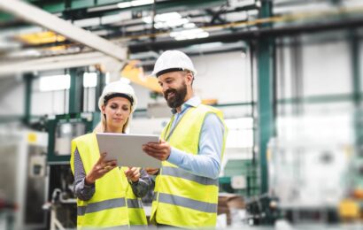 A portrait of an industrial man and woman engineer with tablet in a factory, talking.