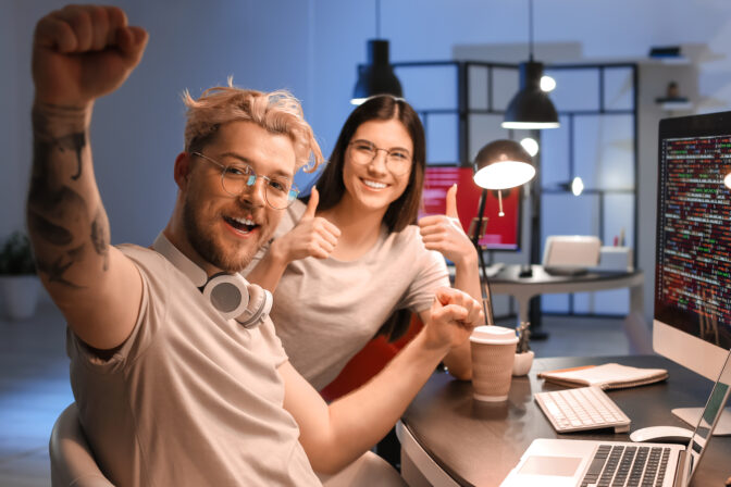 Happy young programmers working in office at night