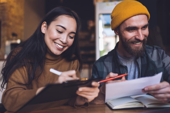 Cheerful male and female students enjoying brainstorming meeting