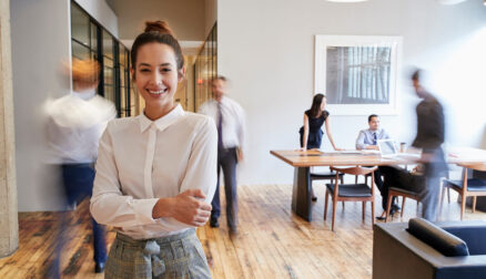 Portrait of young white woman in a busy modern workplace