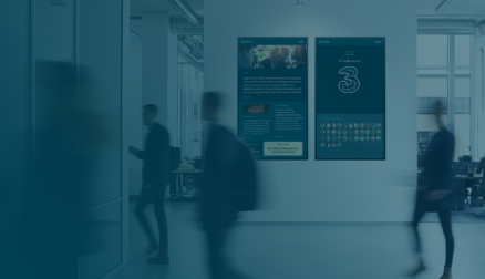 Medarbetare passerar framför digital signage skärmar.